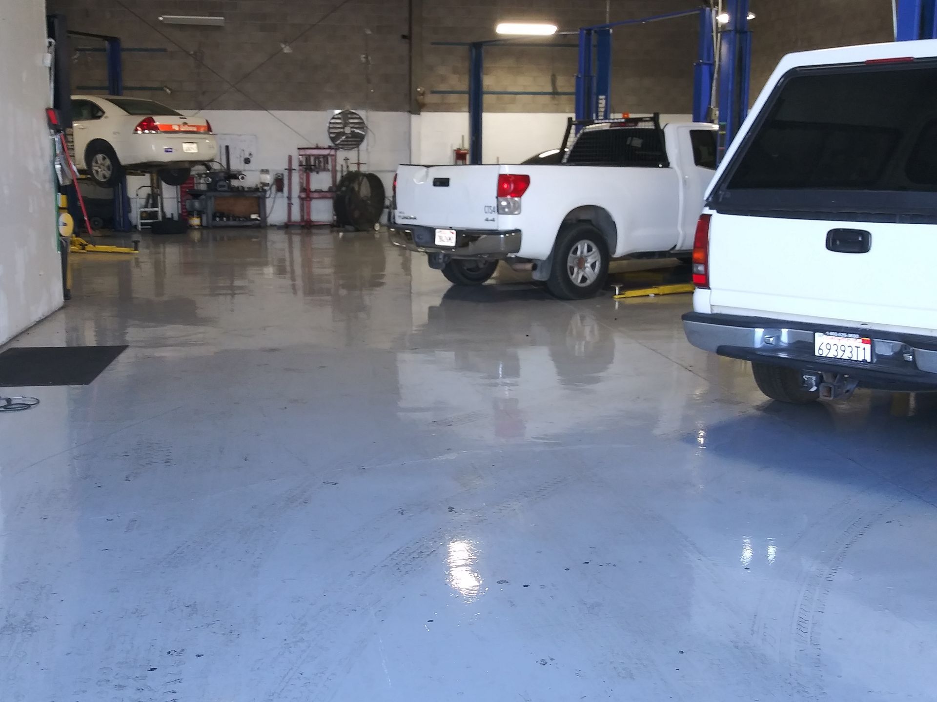 Indoor auto garage with three pickup trucks and a wet, reflective concrete floor | Polar Bear Auto Care