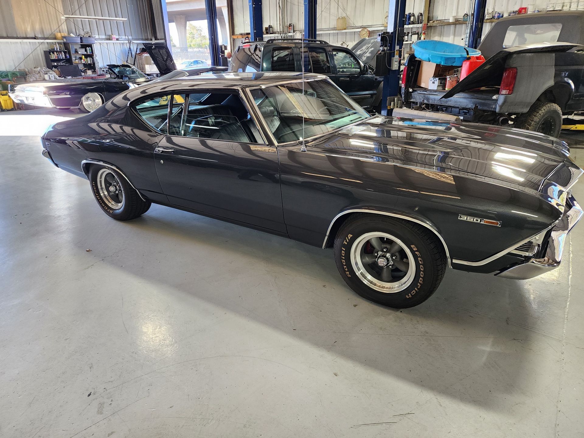 Black classic muscle car in a garage, side view with chrome trim and whitewall tires. | Polar Bear Auto Care