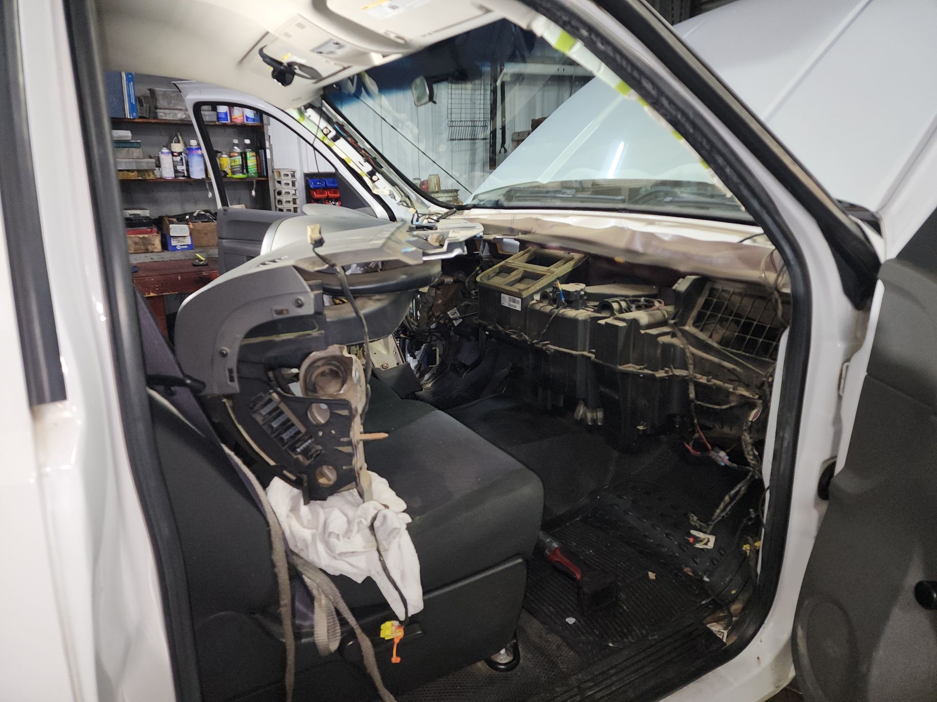 Car interior mid-repair, dashboard removed with exposed wiring and seats covered in the garage | Polar Bear Auto Care