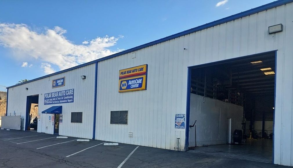 White industrial warehouse exterior with open garage bays and blue sky on a sunny day | | Polar Bear Auto Care