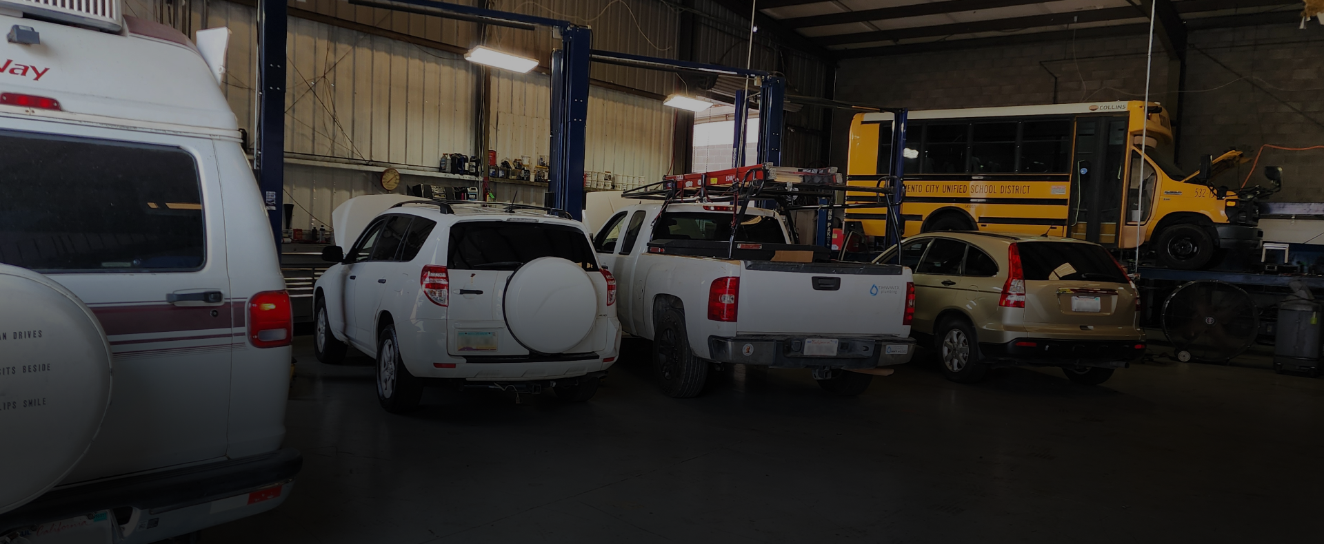 Several SUVs and pickup trucks parked inside a warehouse garage. | Polar Bear Auto Care