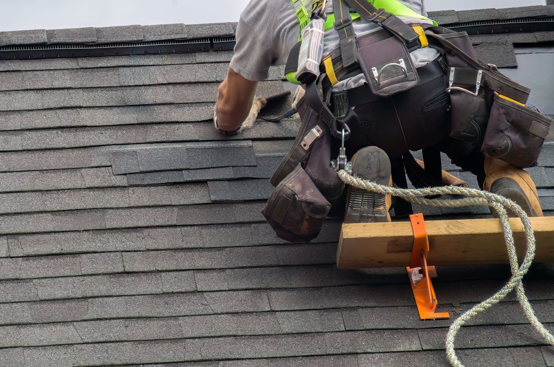 A roofer working on roof maintenance safety with a secure rope provides roofing services.