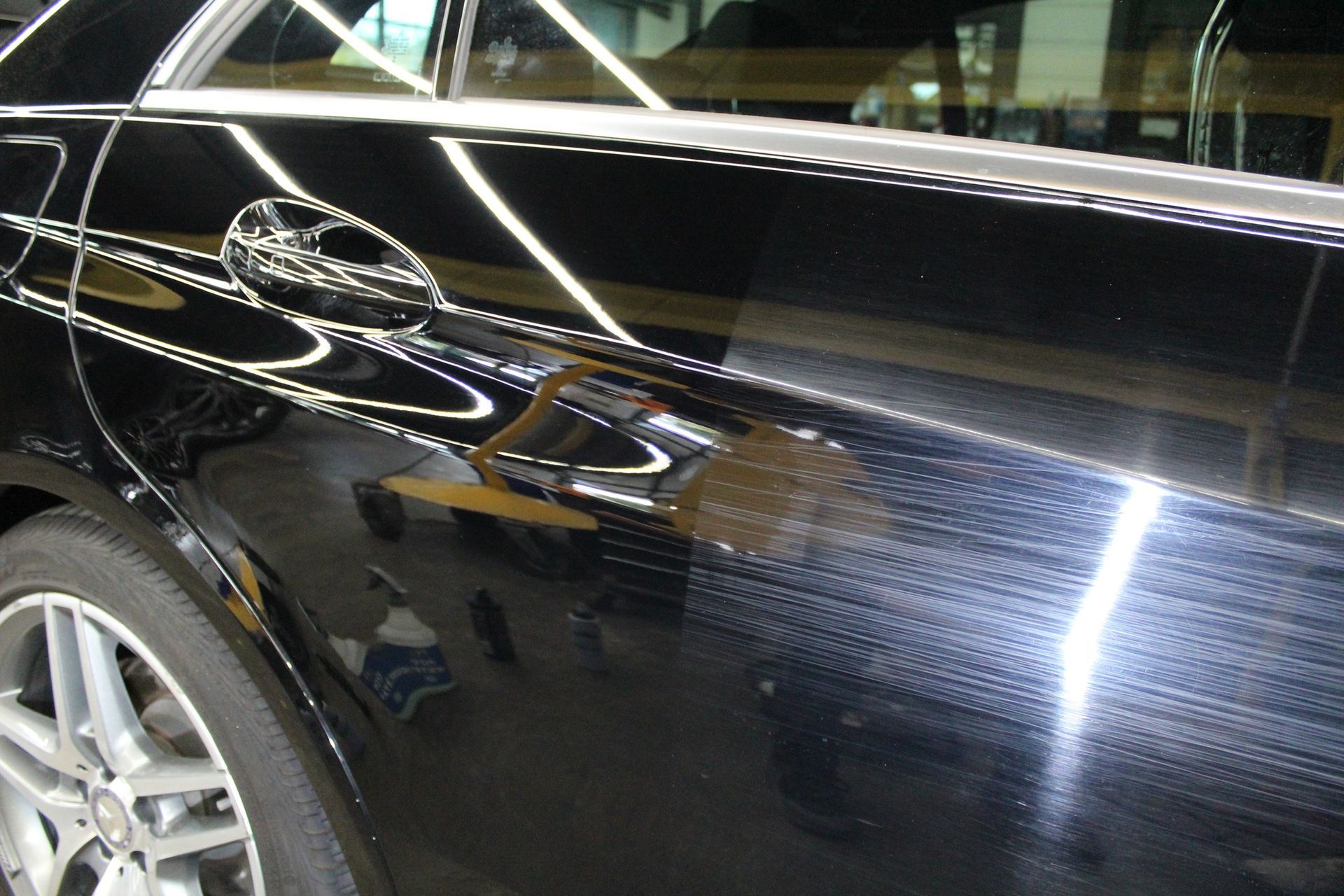 A black car is sitting in a garage with the door open