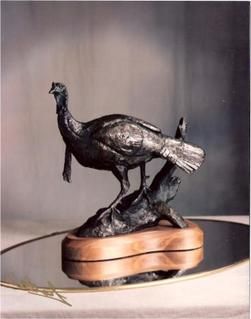 A bronze statue of a bird standing on a tree branch
