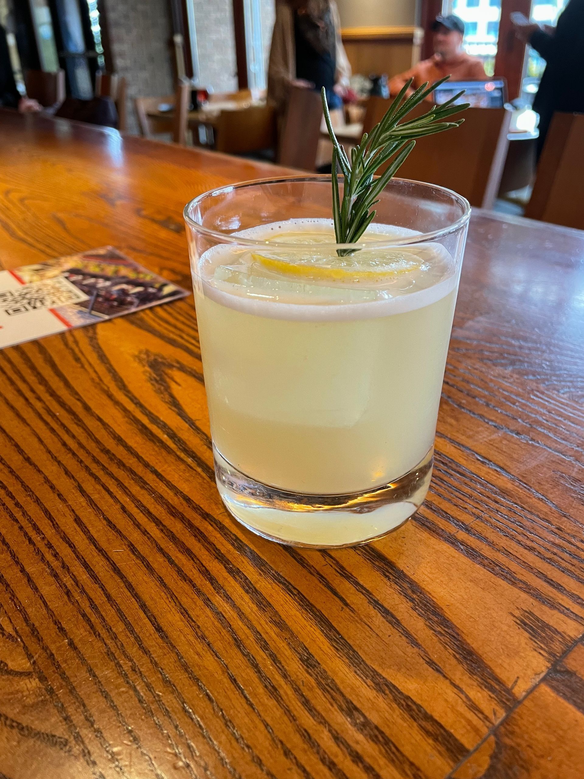 Tall cocktail with red chili rim and lime garnish, on a red cloth.