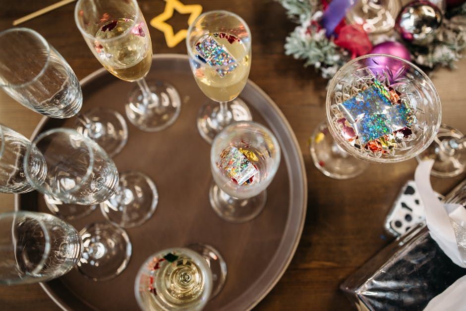 Glasses of champagne and sparkling cocktails on a tray at a festive party table with confetti.