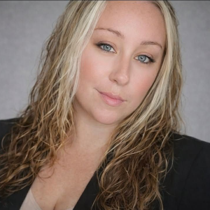 Woman with blonde hair, wearing a dark blazer, looking at the camera with a slight smile.