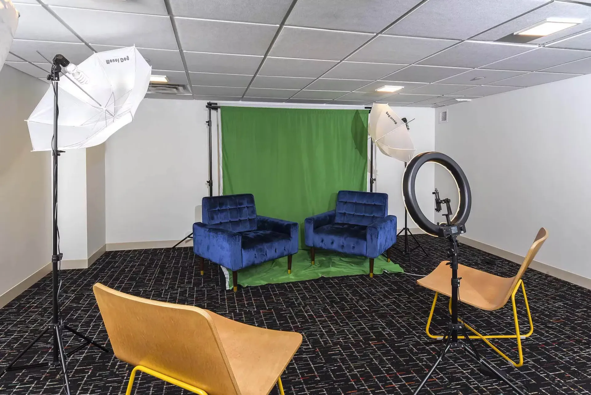 Community podcast studio with green screen backdrop, two blue chairs, and lighting equipment at Terminal 21, a premier apartment community in Downtown Pittsburgh, Pennsylvania.