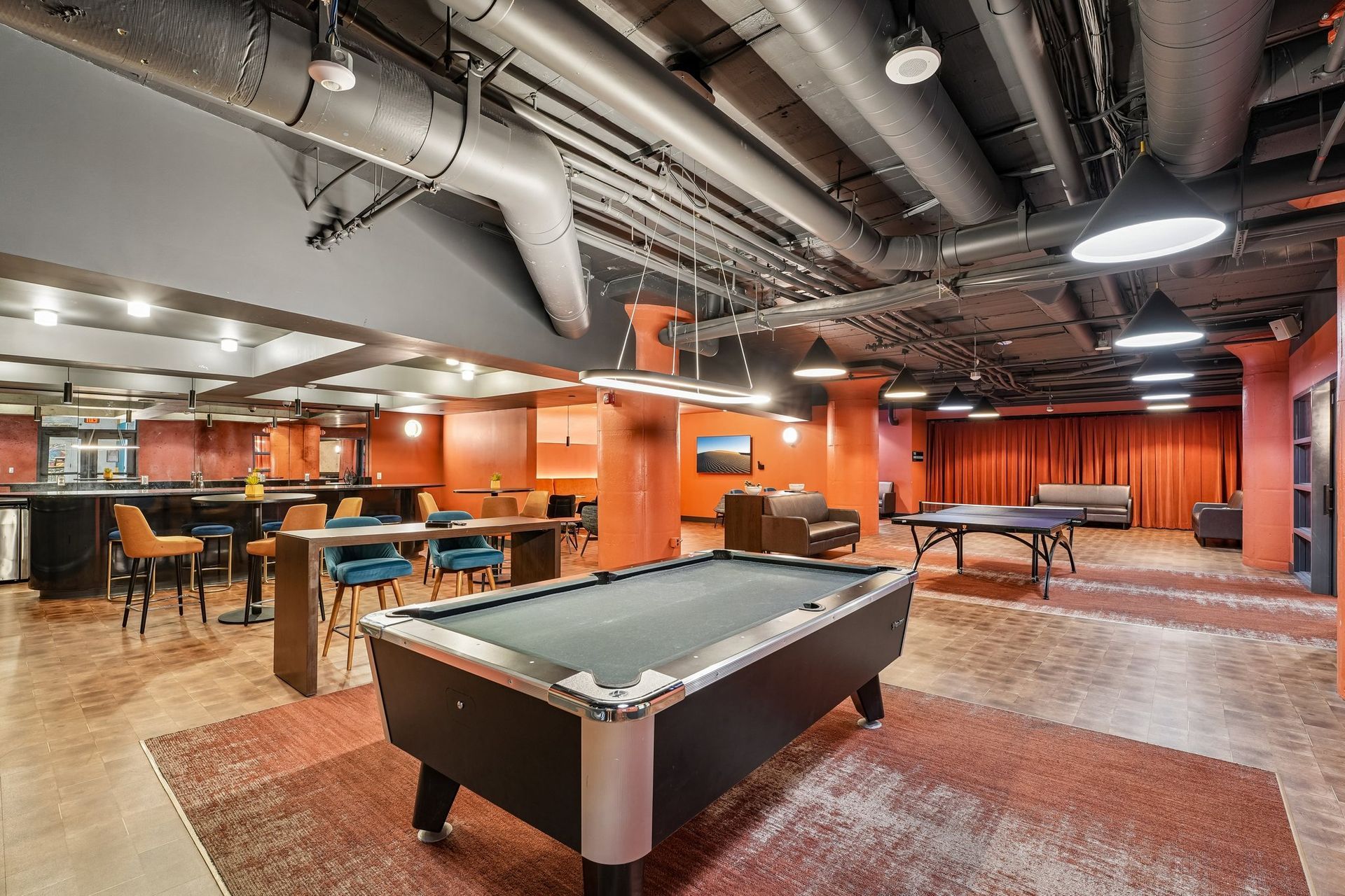 Recreation room with pool table, ping-pong table, and seating in an industrial-style resident lounge at Terminal 21, a premier apartment community in Downtown Pittsburgh, Pennsylvania.