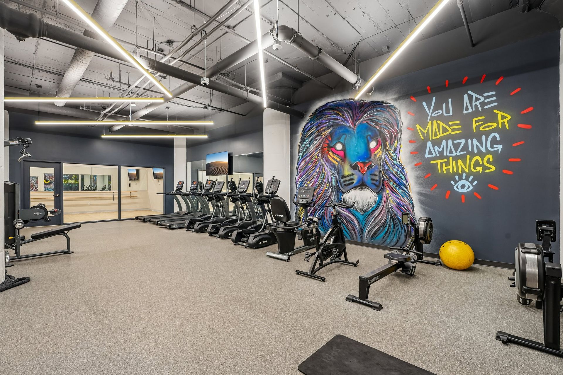 Modern gym with treadmills, mural art wall, and bold text reading “We are made for amazing things” at Terminal 21, a premier apartment community in Downtown Pittsburgh, Pennsylvania.