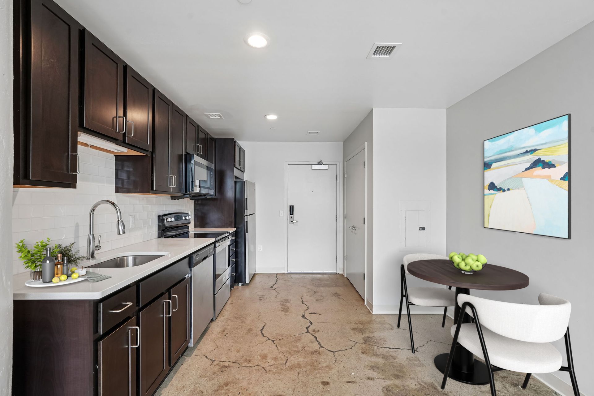 Modern kitchen with dark cabinets, white countertops, and a small dining table in a bright apartment at Terminal 21, a premier apartment community in Downtown Pittsburgh, Pennsylvania.