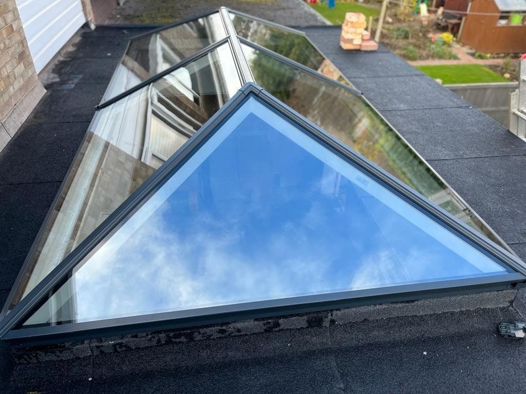 A skylight on the roof of a building with a blue sky reflected in it.