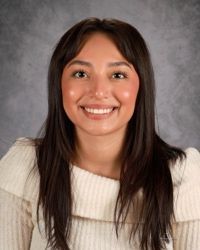 A woman with long black hair is wearing a pink and white striped shirt.