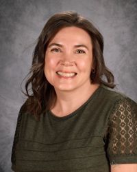 A woman in a floral shirt is smiling for the camera.