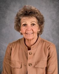 A woman in a pink plaid shirt is smiling for the camera.