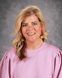 A woman in a red shirt is smiling for the camera.