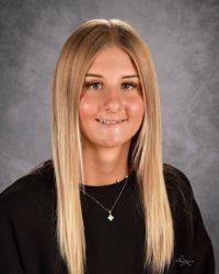 A young woman with long brown hair is smiling for the camera.