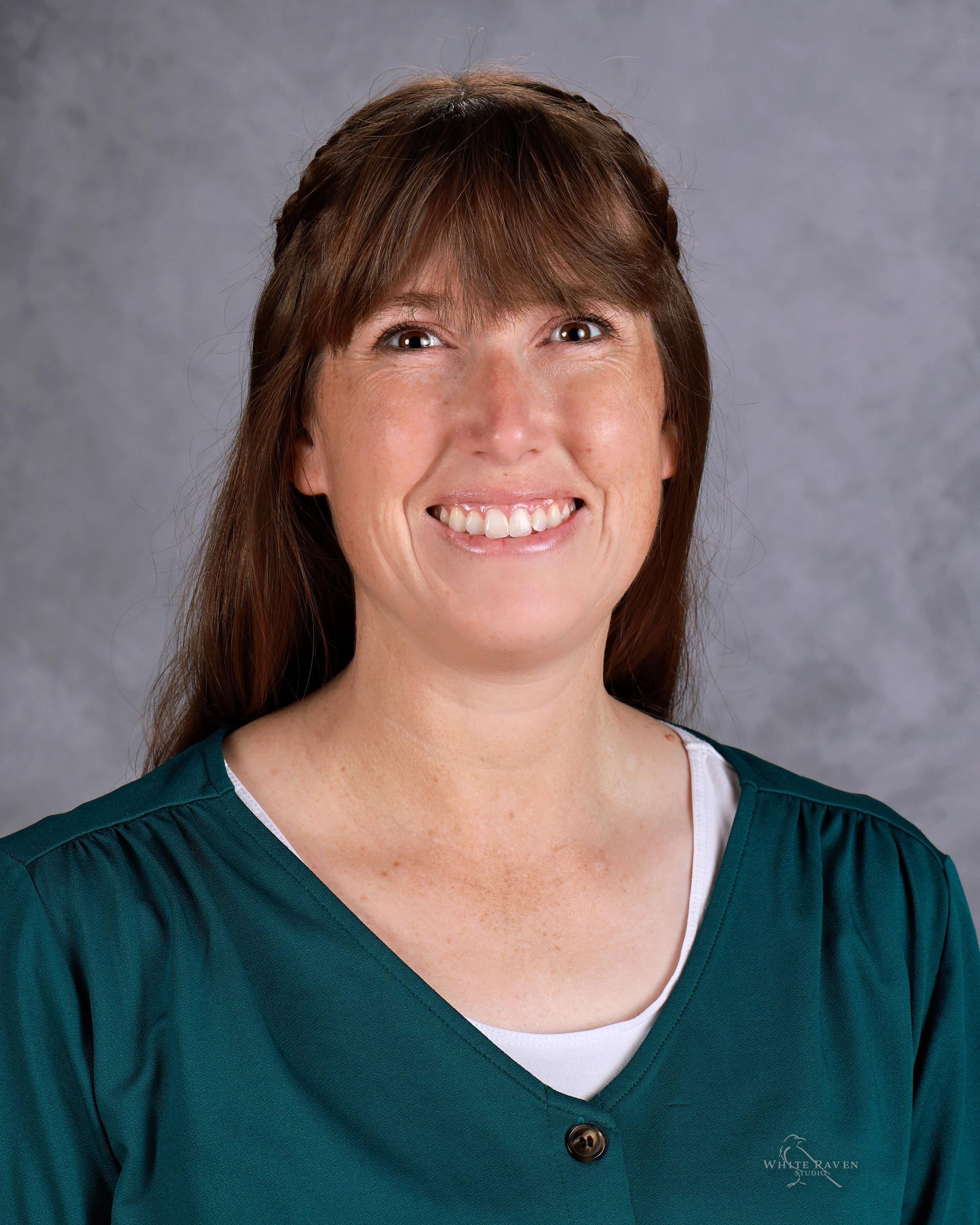 A woman with long hair and bangs is smiling for a picture.