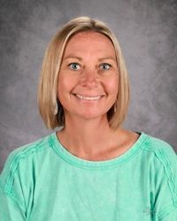 A woman with blonde hair and blue eyes is smiling for the camera.