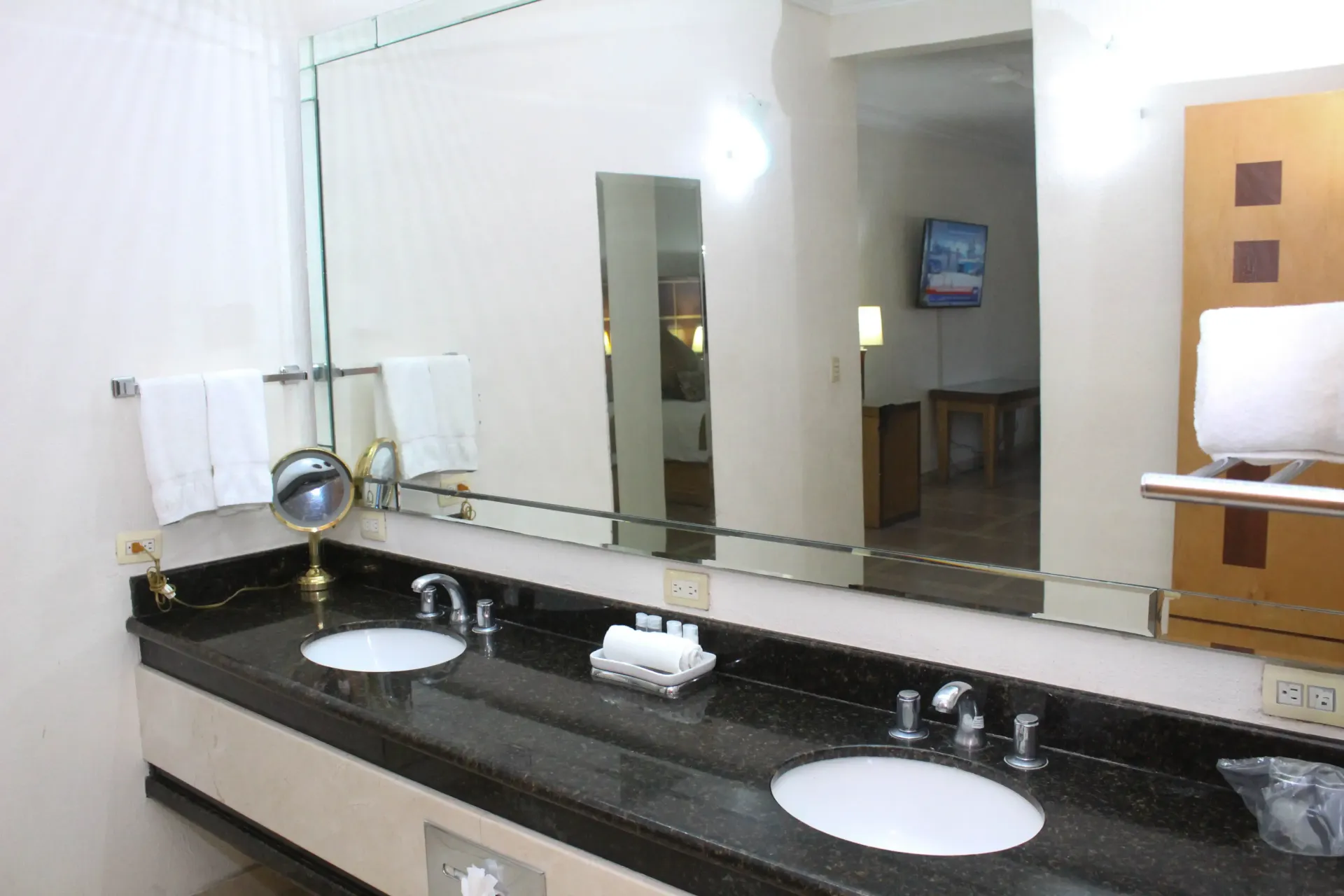 Baño con lavabo doble, espejo grande y toallas. Colores neutros, diseño moderno.