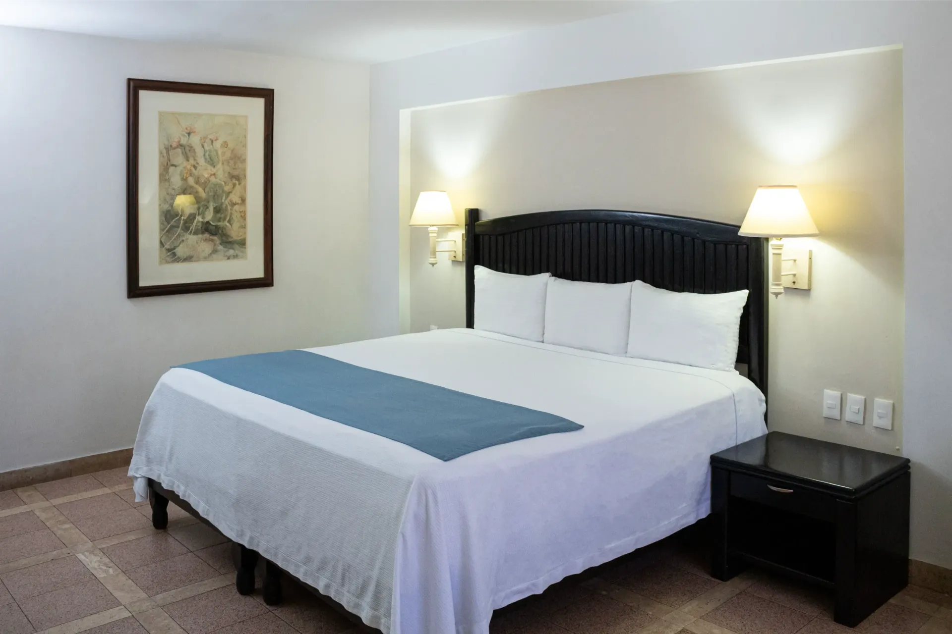 Habitación de hotel con cama, mesita de noche y decoración de pared.