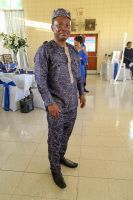 Man in patterned outfit and cap standing indoors on a tiled floor at an event venue