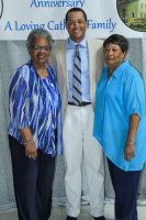 Three people posing indoors in front of a banner, wearing blue and gray clothing.
