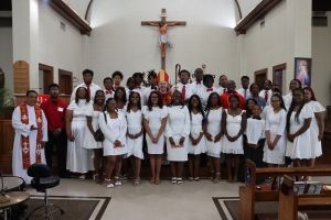 Group of people in white clothing standing in a church before a crucifix