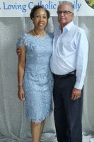 Two people posing together in formal attire, standing in front of a gray backdrop.
