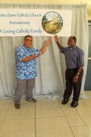 Two men standing and high-fiving in front of a church banner and draped backdrop