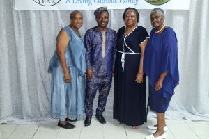 Four people posing indoors in coordinated blue and black outfits before a backdrop