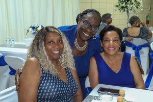 Three people smiling at a banquet table with blue-and-white decor