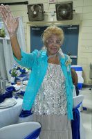 Woman in a turquoise jacket waving at a decorated indoor event