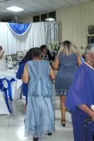 People walking in a decorated indoor hall with blue and white drapes and plastic chairs
