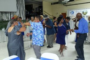 People dancing at an indoor party, with a stage in the background.