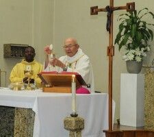 Priest celebrating Mass at altar with chalice and crucifix in a church setting