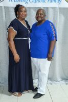 Two smiling adults posing together at an indoor event, wearing navy and blue tops with light backgrounds.