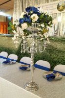 Tall silver floral centerpiece with white and blue flowers on a decorated banquet table