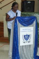 Person speaking at a podium draped in blue and silver fabric, with a speaker behind them.