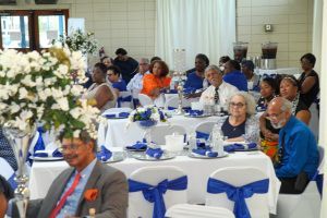 Banquet hall with guests seated at round tables decorated with blue and white bows