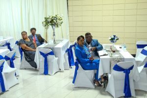 Guests seated at white tables with blue chair covers in a decorated banquet hall