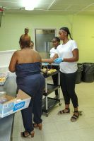 People standing at a table in a room, with boxes and supplies visible.