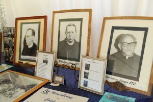 Framed black-and-white portraits and display cards on a table, likely a memorial exhibit