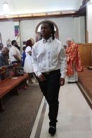 Person in a white shirt and black pants walking down a church aisle during a formal event
