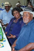 Three people in hats seated at a table, smiling in a casual indoor gathering.