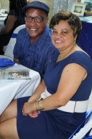 Two smiling people seated together at a table, wearing blue and navy clothing.