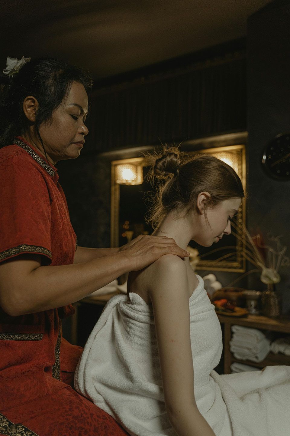 Woman receiving a shoulder massage from a masseuse in a spa setting.