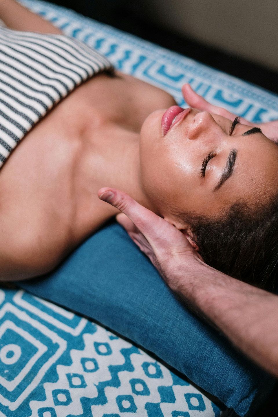 Person receiving a facial massage on a massage table. Hands on their face.