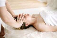 Spa therapist giving a facial massage to a client lying on a treatment table