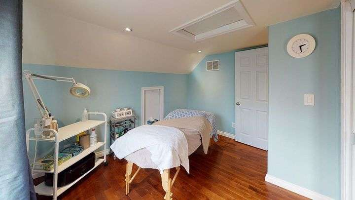 Spa room with treatment bed, equipment, and shelves against blue walls and wood floor.